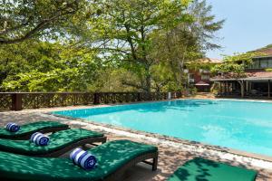 a swimming pool with two green chaise lounge chairs next to it at Tree of Life Nature Resort in Kandy