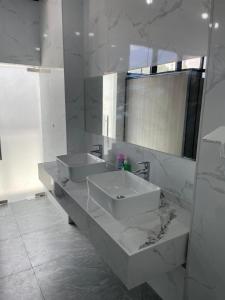 a white bathroom with two sinks and a mirror at Sanibelle Hotel in Coron
