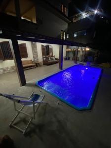 a swimming pool at night with a chair and a chaise lounge at Casa com piscina Perto Da Praia Em FIGUEIRA in Arraial do Cabo