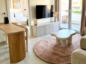 a living room with a table and a tv at Covea by the Sea Boho Seaside Apartment, 400 m from the Beach in Perea