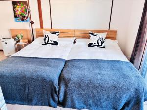 a bed with blue and white sheets and pillows at 蓮子川Room in Hamamatsu