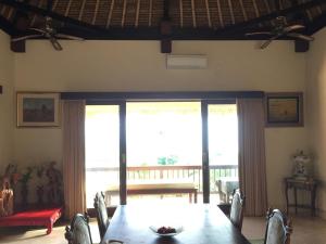 a dining room with a table and chairs and windows at Singa Villas in Ungasan