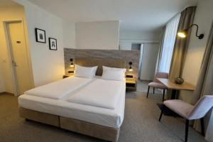 a bedroom with a large white bed and a chair at DORMERO Aparthotel Stralsund in Stralsund