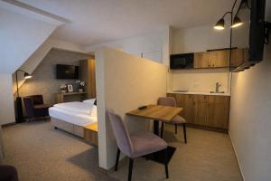 a hotel room with a bed and a table and chairs at DORMERO Aparthotel Stralsund in Stralsund