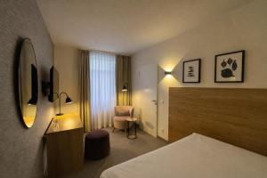 a hotel room with a bed and a chair at DORMERO Aparthotel Stralsund in Stralsund +14 photos