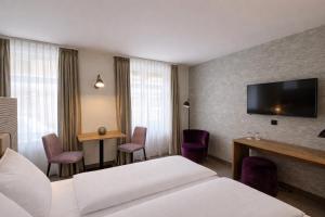a hotel room with a bed and a flat screen tv at DORMERO Aparthotel Stralsund in Stralsund