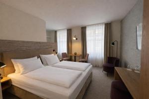 a hotel room with a large white bed and a table at DORMERO Aparthotel Stralsund in Stralsund
