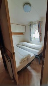 two beds in a small room with a window at Luiwagen in Raalte