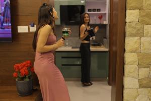 a woman standing in a kitchen holding a glass at Mastiff Citadel RC in Chūharpur +25 photos