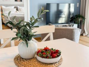 a white vase and a bowl of strawberries on a table at Ferienwohnung Seeglück am Dümmer See in Lembruch