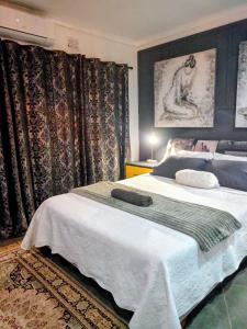 a bedroom with a bed with a white blanket and curtains at Vanilla Lee Guest House in Richards Bay