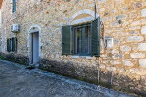 a stone building with green shutters and a window at Green Blue Kardamyli in Kardamyli +41 photos