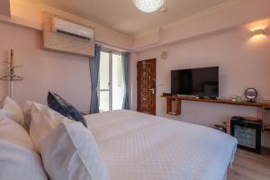 a bedroom with a white bed and a television at Sea Dragonfly in Yanliau