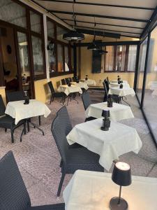 ein Restaurant mit Tischen und Stühlen mit weißen Tischdecken in der Unterkunft Hotel Villa Edera in Lido di Venezia + 30 Fotos
