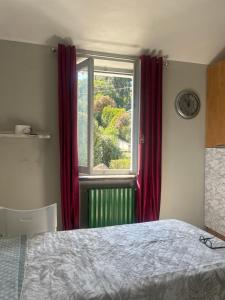a bedroom with a bed and a window with red curtains at Pino Center in Pino Torinese +7 photos
