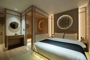 a bedroom with a large bed and two mirrors at Anook Ryokan Hotel Daejeon Yuseong in Daejeon