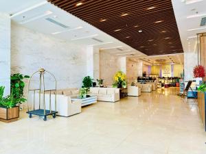 a lobby with white furniture and plants in a building at Yarra Ocean Suites Danang in Danang +91 photos