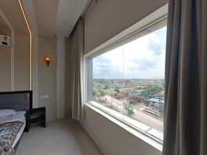 a bedroom with a large window with a view at Hotel Plain A Quiet Stay in Mubārikpur