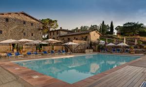 a large swimming pool with chairs and umbrellas at Borgo Il Poggiaccio Residence in Sovicille