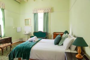 a bedroom with a large bed with a green blanket at The Manor House at Dunn's Castle in Piketberg +7 photos
