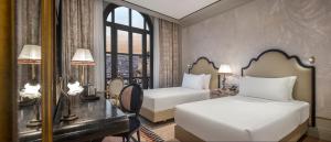 a bedroom with two beds and a desk and a window at Palazzo Donizetti Istanbul, Tapestry Collection by Hilton in Istanbul