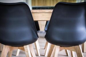 デ・ハーンにあるEen briesje aan zeeの木製テーブルの横に座る黒い椅子2脚