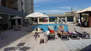 Eine Frau im Badeanzug liegt auf Stühlen an einem Pool. in der Unterkunft RPT 1 -Prive das Thermas 405 C in Caldas Novas