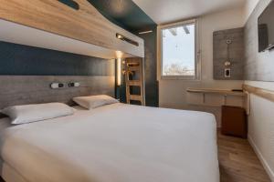 a bedroom with a large white bed and a window at Ibis Budget Le Havre Les Docks in Le Havre