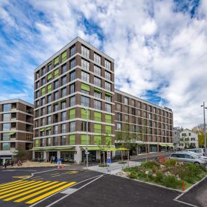 a tall building on a street with a parking lot at Zleep Hotel Zürich-Kloten in Kloten