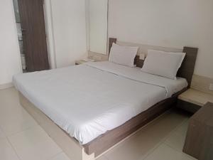 a large bed with white sheets and white pillows at Hotel Paras in Junagadh