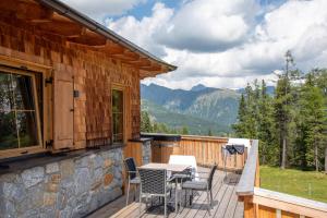 a deck with a table and chairs on a house at Bockspitze Deluxe Appartements in Hinterweisspriach