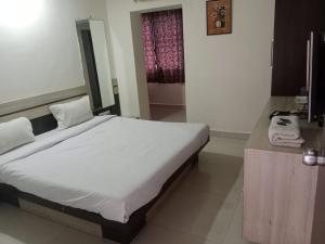 a bedroom with a large bed and a bathroom at Hotel Paras in Junagadh