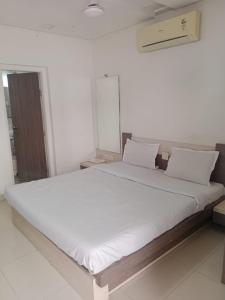 a large white bed in a white room at Hotel Paras in Junagadh