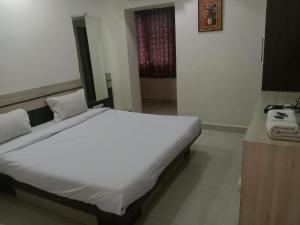 a bedroom with a large white bed in a room at Hotel Paras in Junagadh