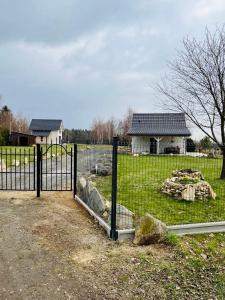 a fence in front of a field with a house at Cudne Manowce ogrodzony domek na wyłączność wśród ciszy i natury u stóp Gór Izerskich in Giebułtów