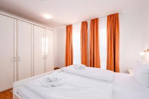 a bedroom with two white beds with orange curtains at Strandhaus Lobbe, Sanddorn Nr 3 - Bade- & Saunawelt täglich inklusive in Lobbe +14 photos
