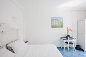 a white bedroom with two beds and a table at Hotel Bussola in Anacapri +40 photos