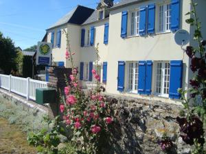 una casa con persianas azules y flores en La Maison Claire, en Longueville