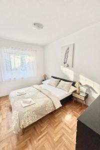 a white bedroom with a bed and a wooden floor at Apartment Olivia in Šmrika