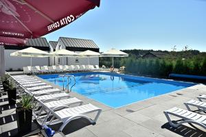 a swimming pool with lounge chairs and an umbrella at Skorzęcin Rybakówka Resort in Skorzęcin
