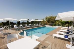 a pool with chairs and tables and umbrellas at Hotel Bussola in Anacapri