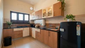 a kitchen with wooden cabinets and a black refrigerator at Willostays Tamarind beach villa in Cherai Beach