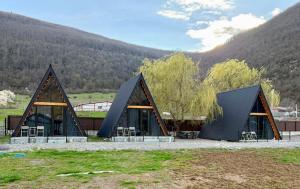 two triangular buildings with tables and chairs in a field at Kvabtkari Cottages in Ambrolauri