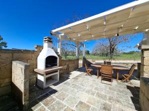 a patio with a wood fired oven and a table and chairs at Le Villette Li Sarruni by SalentoInVacanzaCOM in Lido Marini