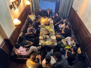 a group of people sitting around a long table in a restaurant at SONDERIA Hostel & Bar - Lazybones in Chengdu