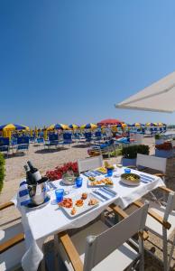 a table with food on the beach with chairs and umbrellas at Hotel Marina in Fano