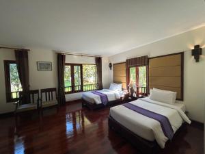 a bedroom with two beds and windows at Teak Garden Resort, Chiang Rai in Chiang Rai +41 photos