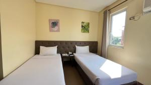 two beds in a room with a desk and a window at Hotel 801 in Cagayan de Oro