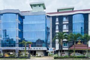 a large blue building with palm trees in front of it at RedDoorz Syariah At Hotel Matahari 1 Jambi in Jambi