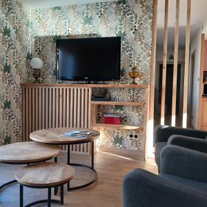 a living room with two tables and a flat screen tv at La D'homette in Fresse-sur-Moselle